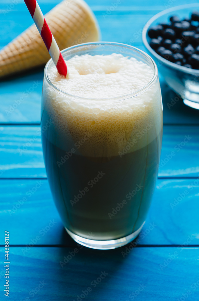 Glass of ice Coffee with cone and bowl of chokeberries on colourful turquoise blue painted wooden boards Glass of ice Coffee with cone and bowl of chokeberries on colourful turquoise blue painted wooden boards