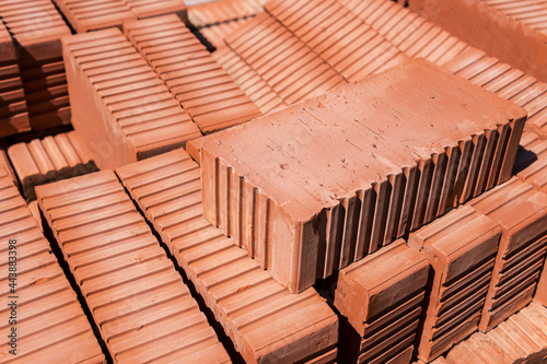 Close-up of a brick lying on top of a stack of red bricks.