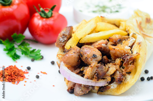 Plate of traditional Greek pita gyros with meat, fried potatoes, tomato and onion