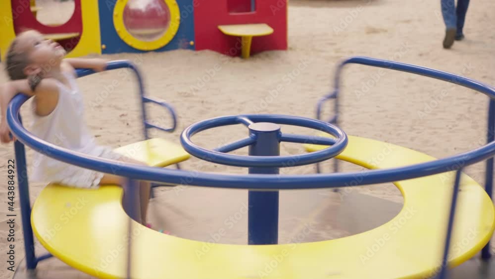 Little Girl Spinning Merry Go Round Carousel Amusement Park Playground Summer Day. Caucasian Female Child 4-5 years old Have Fun Outdoor Active Leisure Little Girl Spinning Merry Go Round Carousel Amusement Park Playground Summer Day. Caucasian Female Child 4-5 years old Have Fun Outdoor Active Leisure