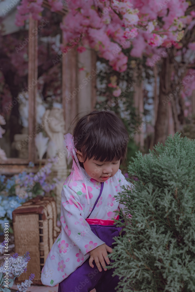 Adorable little girl wearing Japanese kimono in the park with soft focus.