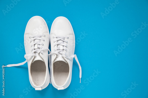 White leather sneakers with laces on blue background