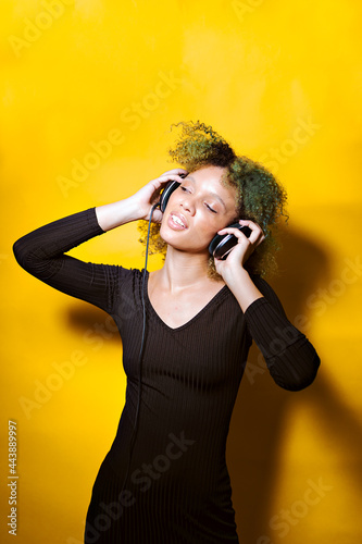 Young afro woman listen music on headphones on colorful background positive concept