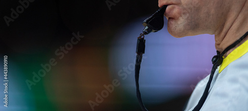Referee with whistle on colorful background. Professional sport concept photo