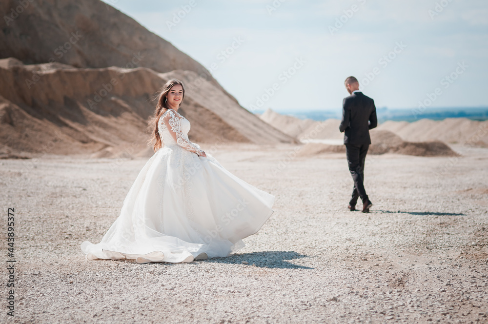 Newlyweds walk and hug in a sandy quarry Newlyweds walk and hug in a sandy quarry
