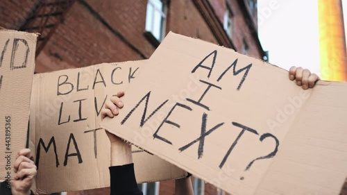 Protesters on the street hold posters above their heads with inscriptions - I STAND WITH YOU, BLACK LIVES MATTER, AM I NEXT