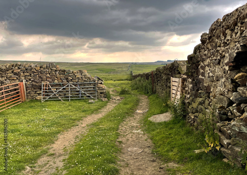 Heavy rain clouds  high on the moors  with a cart track  and a stone sheep pen near  Keighley  UK