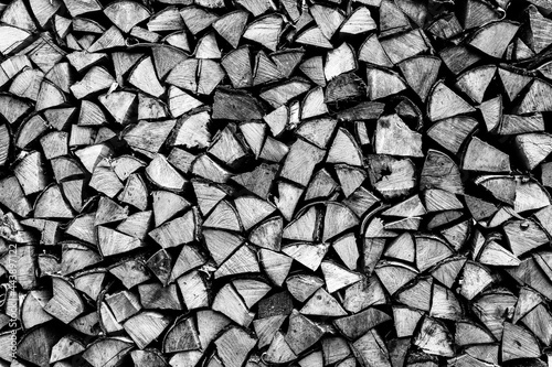 textured firewood background of chopped wood for kindling and heating the house. a woodpile with stacked firewood. the texture of the birch tree. toned in black white or gray color