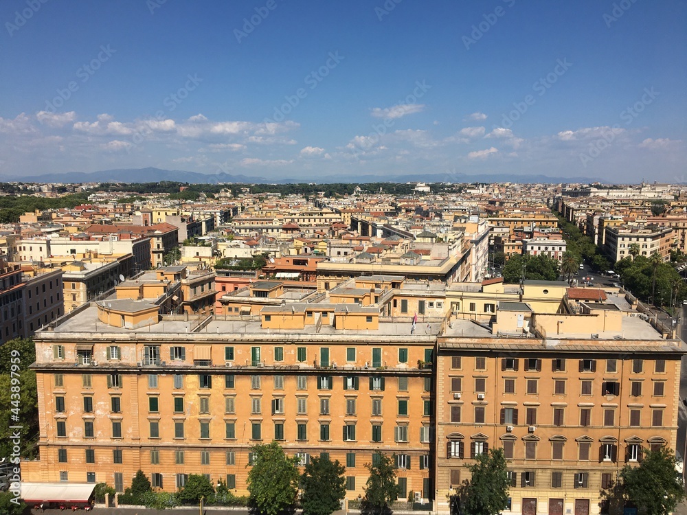 City view on a clear day. Residential buildings and streets from above. Blue summer sky with clouds. Vatican City