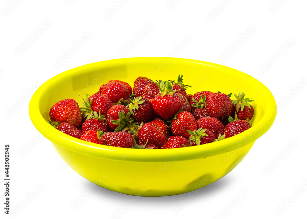 a lot of strawberries with green tails in a large yellow basin. concept of picking berries and teasing. a lot of strawberries with green tails in a large yellow basin. concept of picking berries and teasing.