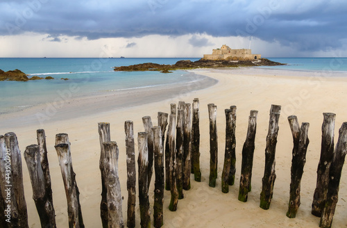 Fort National in Saint-Malo and breakwater trunks at eventail beach