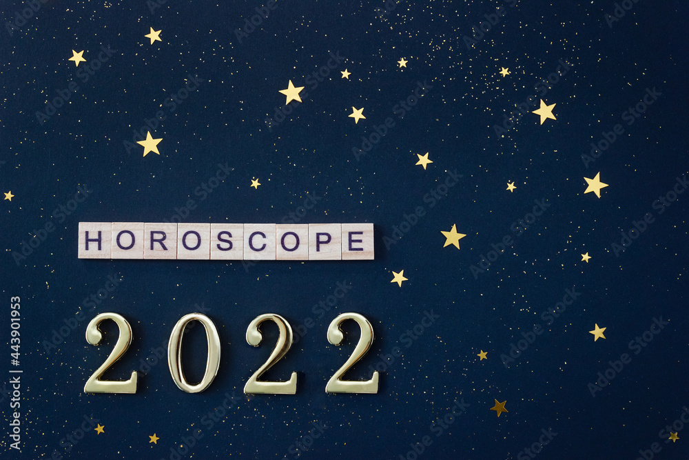 Word Horoscope and numbers 2022. Wooden blocks with letters on blue background decorated with starry confetti. Template for astrological calendar. Selective focus