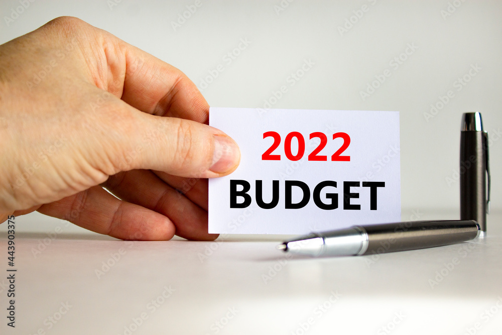 2022 budget new year symbol. White paper with words '2022 budget' in businessman hand, metallic pen. Beautiful white background. Business and 2022 budget new year concept. Copy space. 2022 budget new year symbol. White paper with words '2022 budget' in businessman hand, metallic pen. Beautiful white background. Business and 2022 budget new year concept. Copy space.