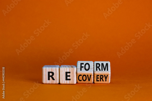 Recovery and reform symbol. Turned wooden cubes and changed the word 'recovery' to 'reform'. Beautiful orange background. Business and recovery - reform concept. Copy space.