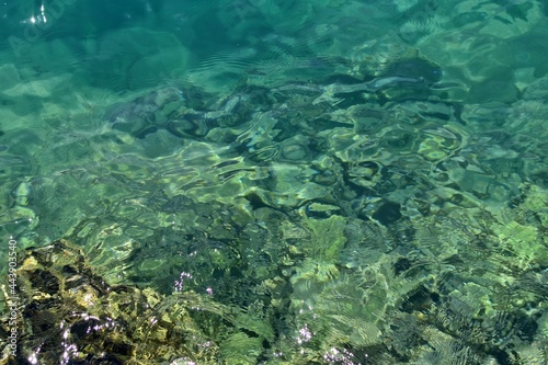 Crystal clear water with blurred seabed and sun reflection