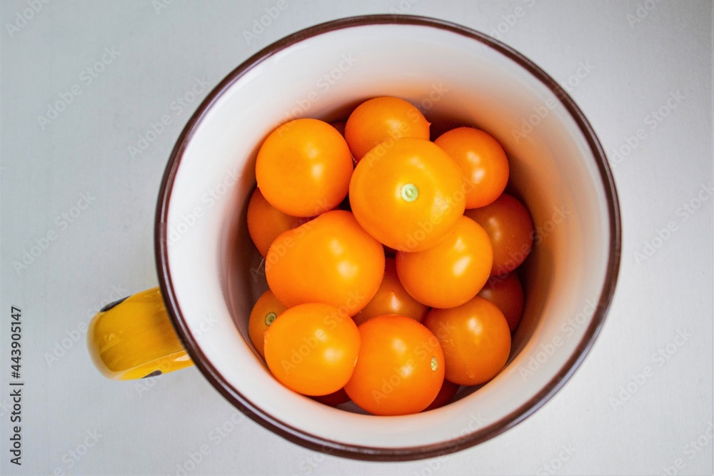 Yellow cherry tomatoes in an iron enamel mug, top view. The focus is on the vegetables and is blurred at the edges of the cup Yellow cherry tomatoes in an iron enamel mug, top view. The focus is on the vegetables and is blurred at the edges of the cup