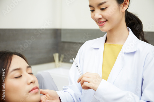 A young beauty doctor plastic surgeon's is conducting the facial filler injection process for a female customer in the beauty salon