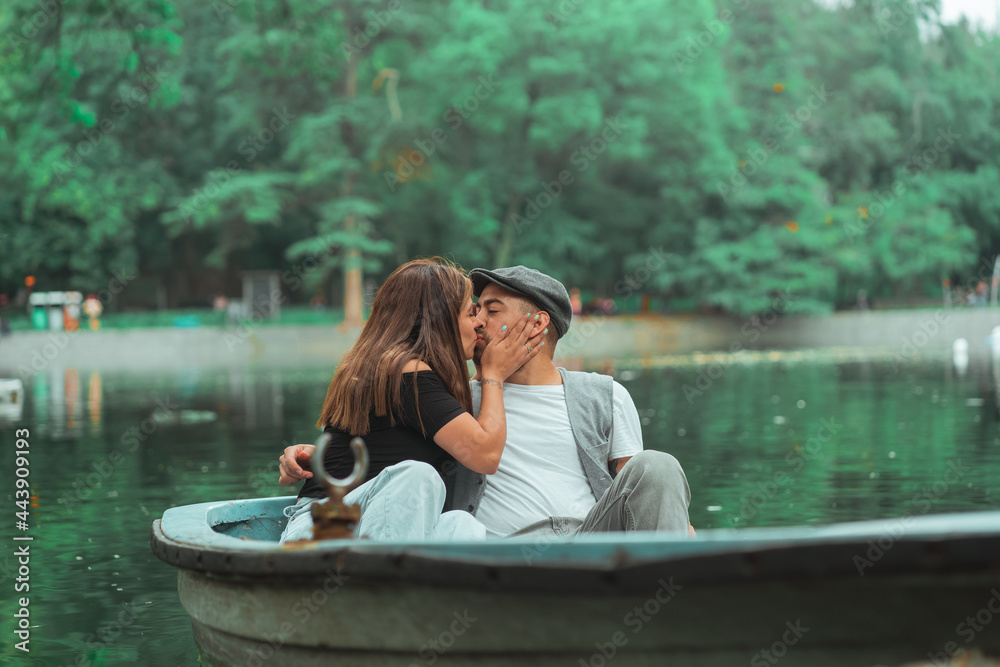Couple kissing sitting in a boat in the middle of a lake