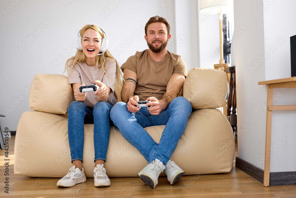 Excited caucasian couple playing video games with television in new apartment. excited and funny for amazing experience in new video game at lving room. Relax and hobby concept. Side view, copy space
