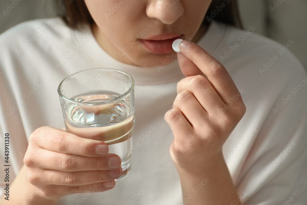 Young woman taking abortion pill on light background, closeup Young woman taking abortion pill on light background, closeup