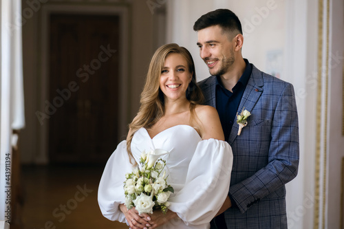 Portrait of a beautiful bride and groom. Happy bride smiling and holding a wedding bouquet. The elegant groom rejoices and embraces his beloved woman. Happy newlyweds on their wedding day
