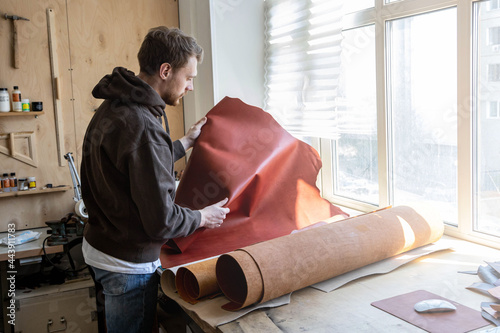 Foto Craftsman unwrapping bundle of stuff natural material working at leather workshop