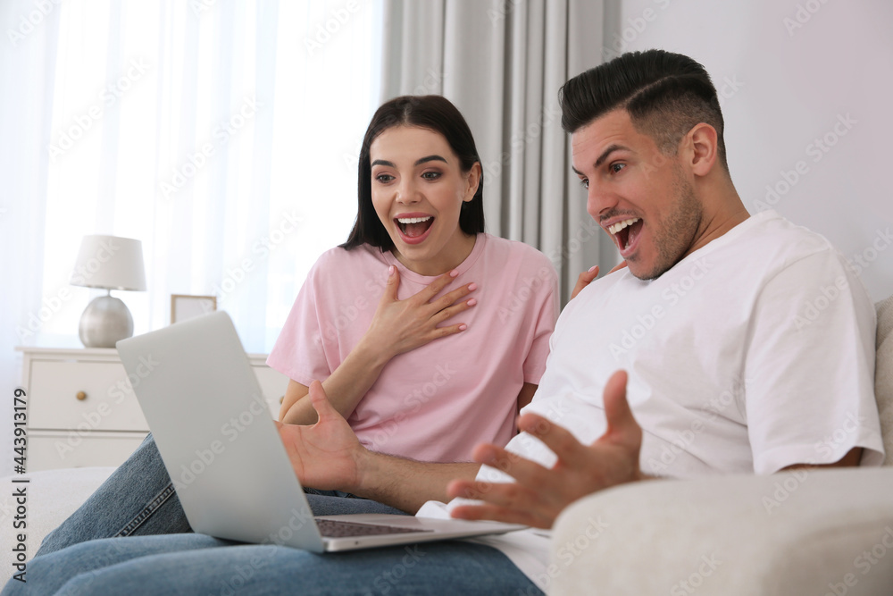 Emotional couple participating in online auction using laptop at home Emotional couple participating in online auction using laptop at home