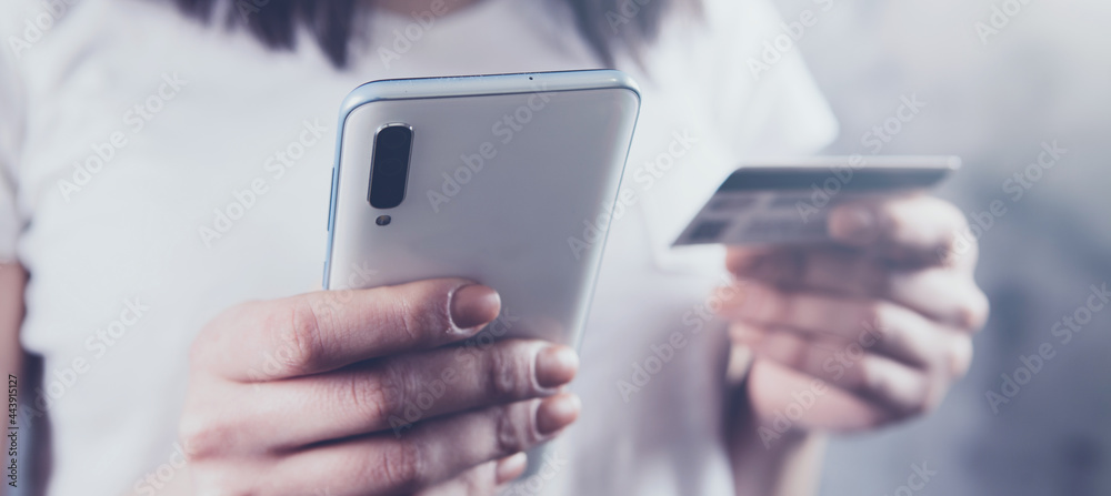 girl holding a phone and a bank card in her hands girl holding a phone and a bank card in her hands
