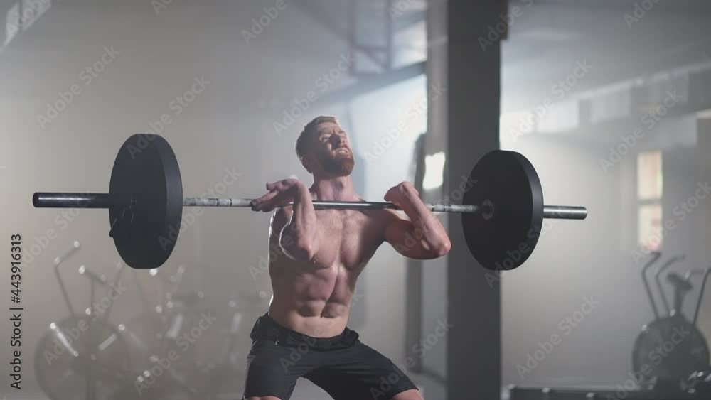 Slow motion: fitness man bodybuilder training using barbell weightlifting exercise muscular sportsman power lifting heavy weight doing squats in gym practice enjoying healthy lifestyle Slow motion: fitness man bodybuilder training using barbell weightlifting exercise muscular sportsman power lifting heavy weight doing squats in gym practice enjoying healthy lifestyle