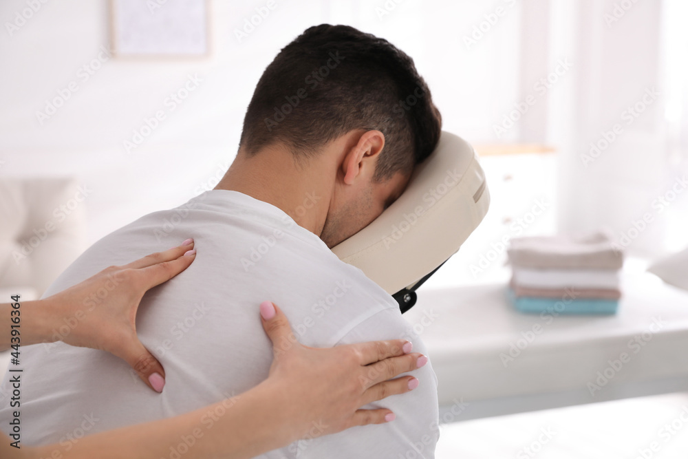 Man receiving massage in modern chair indoors Man receiving massage in modern chair indoors
