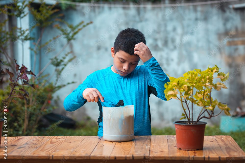 Latino boy stirring dirt on the table to sow