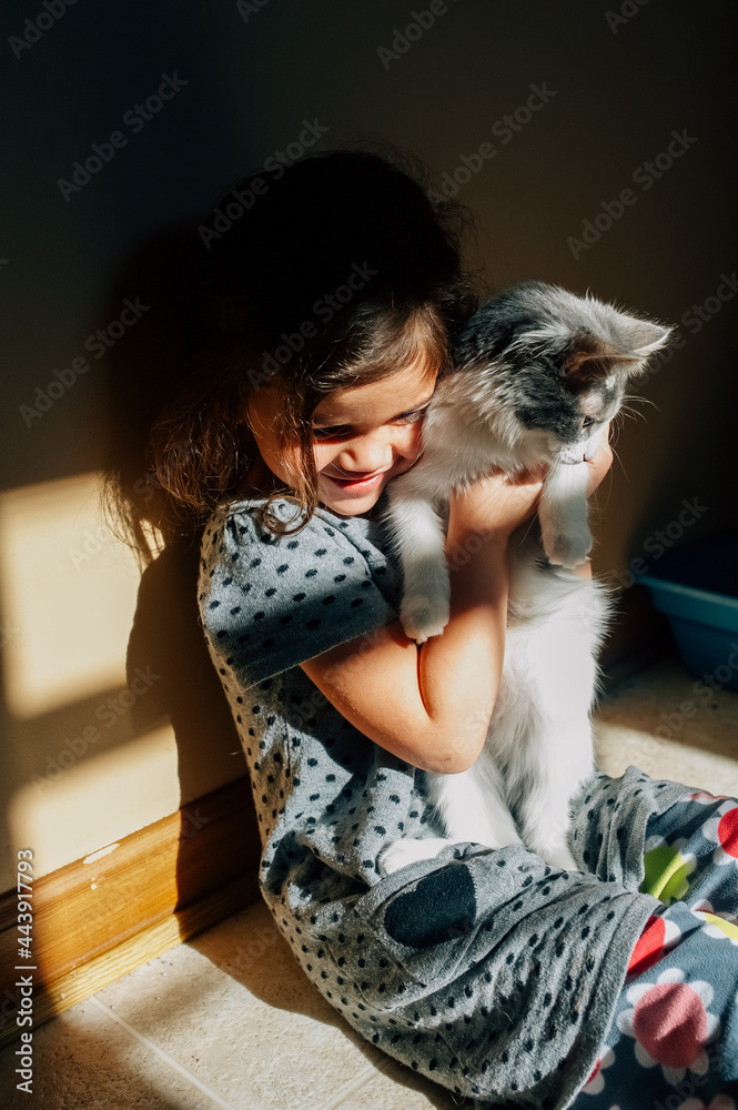 Happy girl snuggling with gray and white kitten. Happy girl snuggling with gray and white kitten.