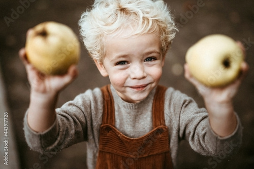 Blond kid showing off pears in his hands