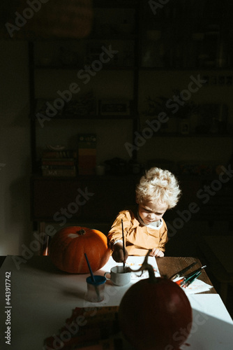 Blond child painting a pumpkin photo