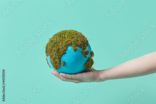 Woman holding earth globe with green moss on hand photo