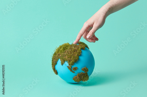 Woman touching earth globe with green moss photo