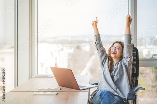 A happy and cheerful businesswoman raising fists with ambition. Personal success and career ladder. Business achievement and promotion concept