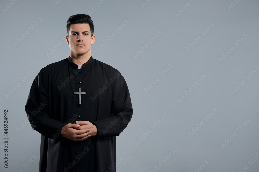 Priest wearing cassock with clerical collar on grey background. space for text Priest wearing cassock with clerical collar on grey background. space for text