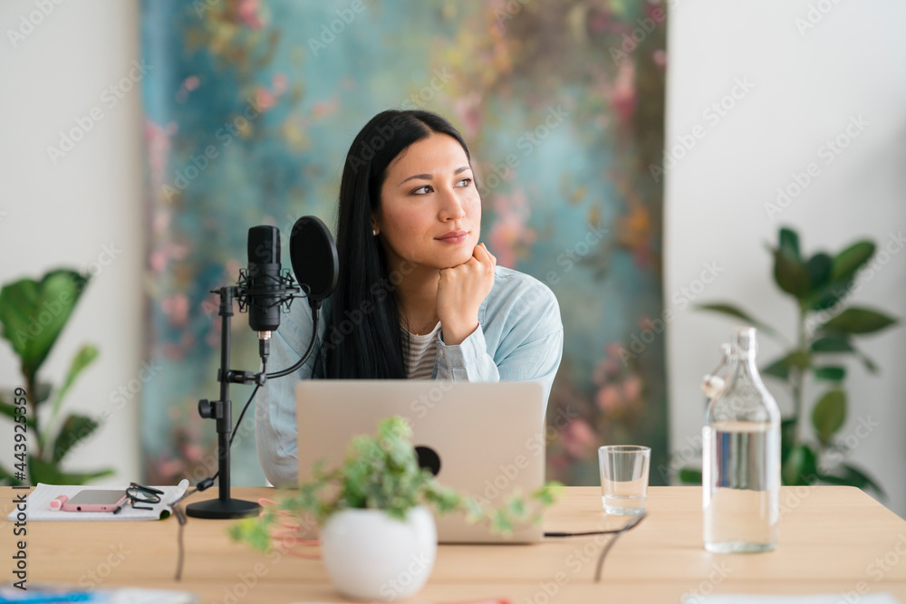 Pensive woman preparing for recording podcast and looking away Pensive woman preparing for recording podcast and looking away