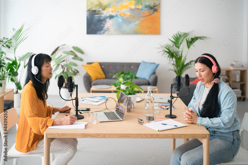 Asian women recording podcast together in studio Asian women recording podcast together in studio