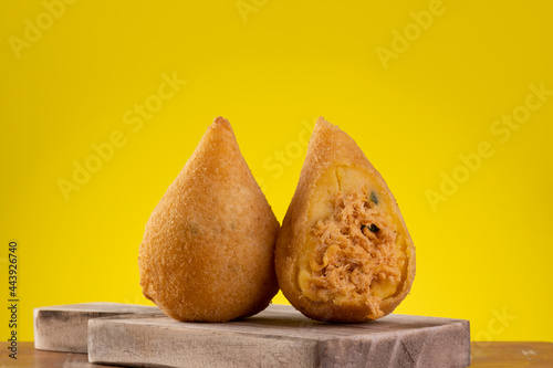 Fried coxinha on wooden board with yellow background photo