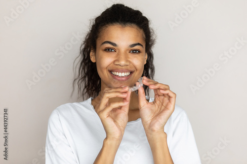 Portrait of african american smiling girl holding dental aligner photo