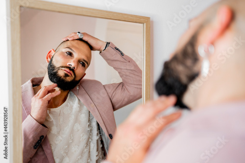 Glamurous man with makeup looking at mirror photo