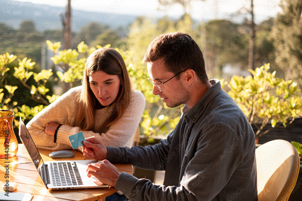 Happy couple buying online using credit card on terrace Happy couple buying online using credit card on terrace