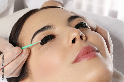 Young woman undergoing eyelash lamination and tint in salon, closeup