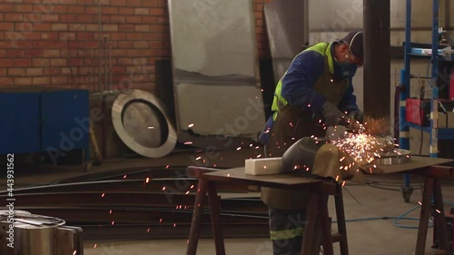 Worker using a grinder and cutting metal in a industrial space, with sparks effect. photo
