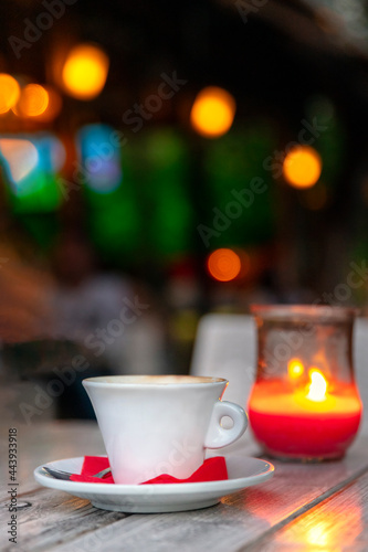 Cup of coffee on a wooden table at night by candle light, outdoors.