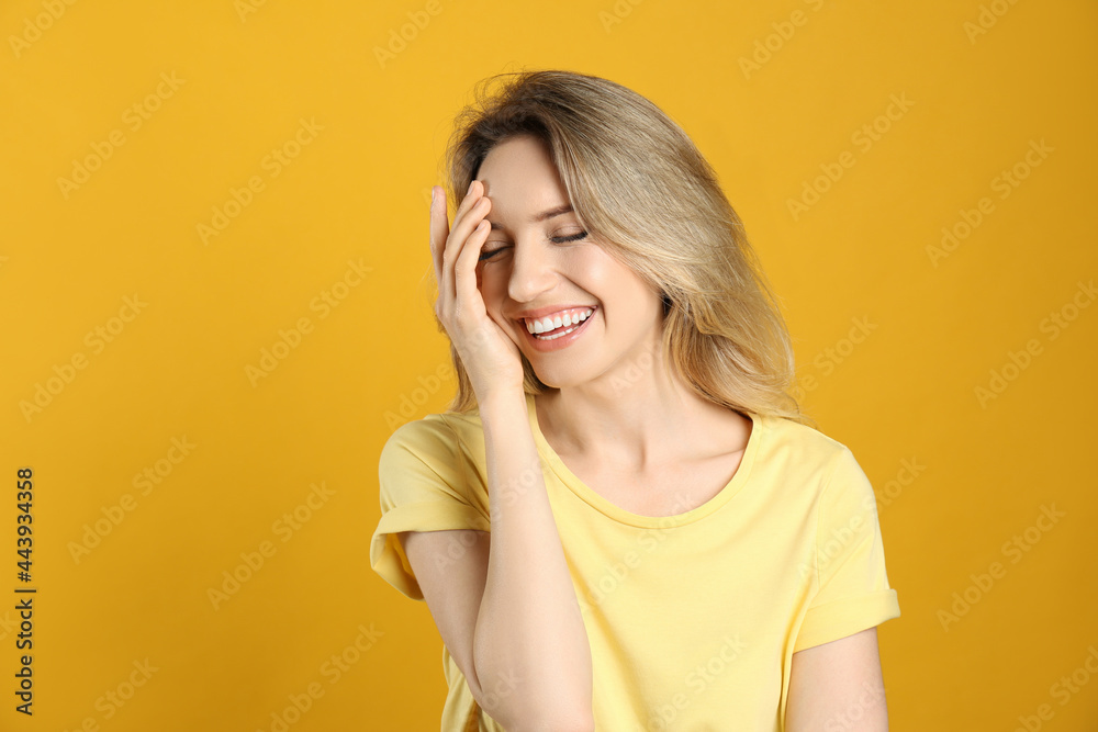 Portrait of happy young woman with beautiful blonde hair and charming smile on yellow background Portrait of happy young woman with beautiful blonde hair and charming smile on yellow background