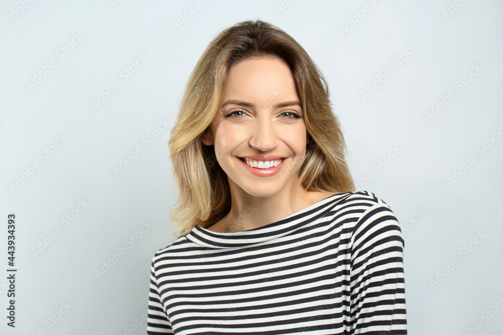 Portrait of happy young woman with beautiful blonde hair and charming smile on light background Portrait of happy young woman with beautiful blonde hair and charming smile on light background