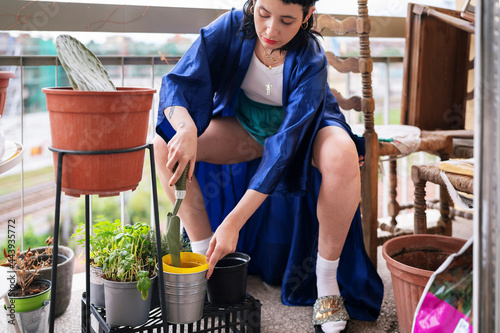 Woman planting potted plant on balcony